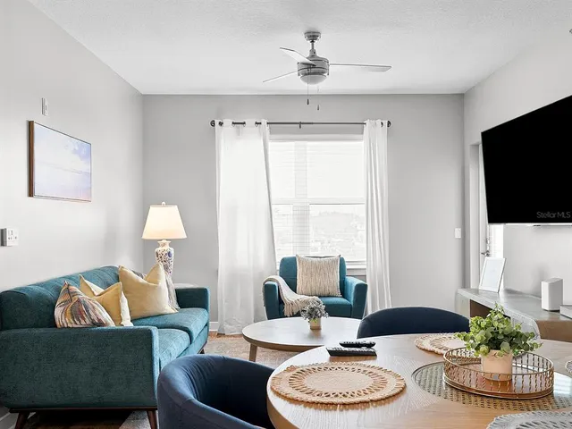 a living room with furniture a flat screen tv and a window