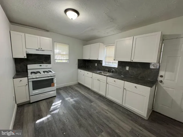 a kitchen with granite countertop a stove a sink and a microwave