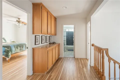 a view of a hallway with wooden floor and a bathroom