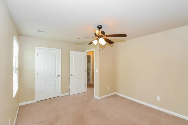 an empty room with a chandelier fan and windows
