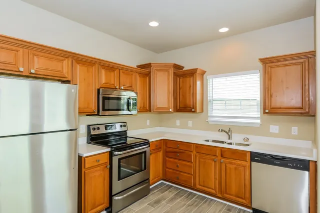 a kitchen with stainless steel appliances granite countertop a refrigerator stove top oven a sink and dishwasher