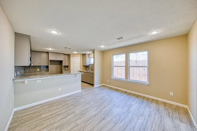 a large kitchen with stainless steel appliances granite countertop a refrigerator a sink dishwasher a stove and white countertops with wooden floor