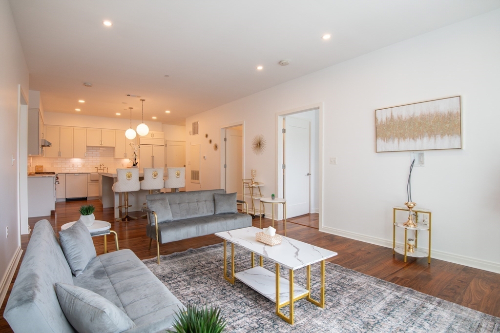 3531 Washington Street, Unit 316 Boston, MA 02130 - Photo 5 of 40 a living room with couches and kitchen view with wooden floor