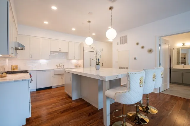 a large kitchen with cabinets wooden floor white stainless steel appliances and dining table