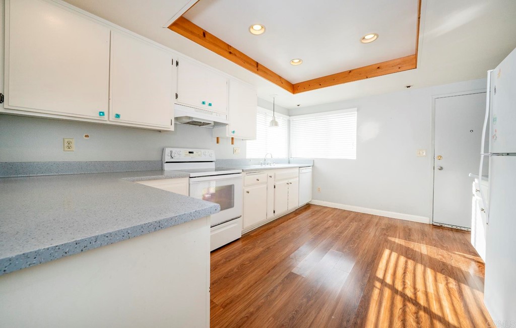 249 Fredricks Avenue Oceanside, CA 92058 - Photo 9 of 31 a large kitchen with stainless steel appliances granite countertop a stove a sink and white cabinets with wooden floor