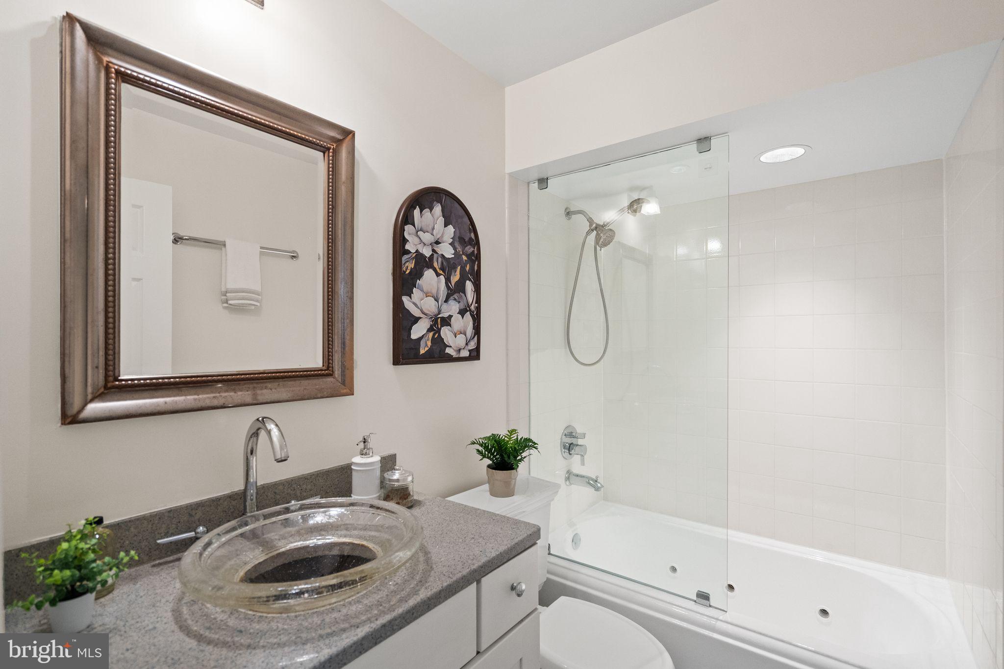 1008 Paper Mill Court, Unit 1008 Washington, DC 20007 - Photo 13 of 31 a bathroom with a granite countertop sink a toilet and shower
