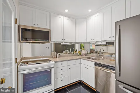 a kitchen with granite countertop white cabinets and stainless steel appliances
