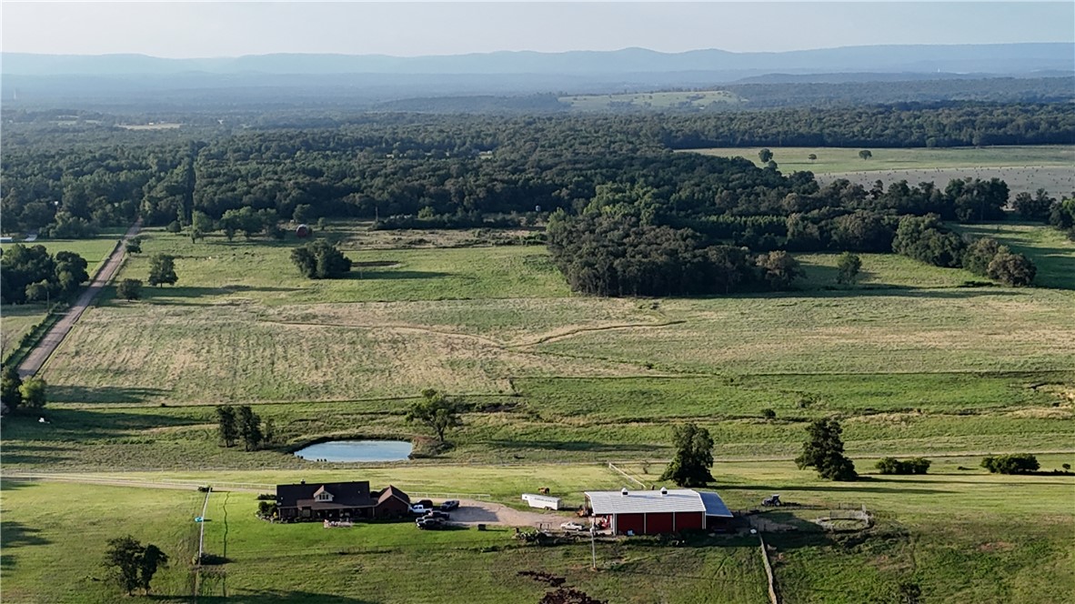 2210 Weiterer Road Scranton, AR 72863 - Photo 34 of 49 Expansive rural property featuring a primary residence, a red barn structure, a prominent pond, a paved driveway, and extensive surrounding acreage with woodlands in the distance