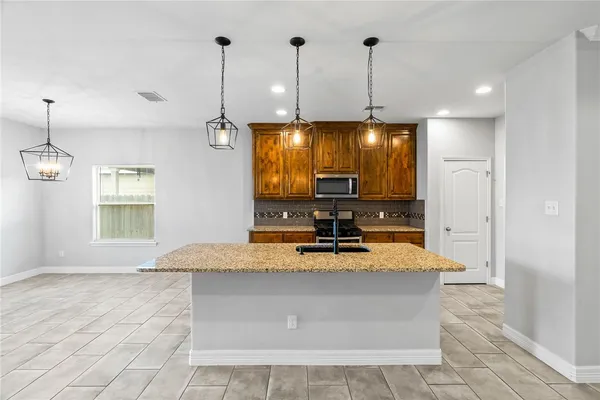 a view of a kitchen with kitchen island stainless steel appliances granite countertop sink and window