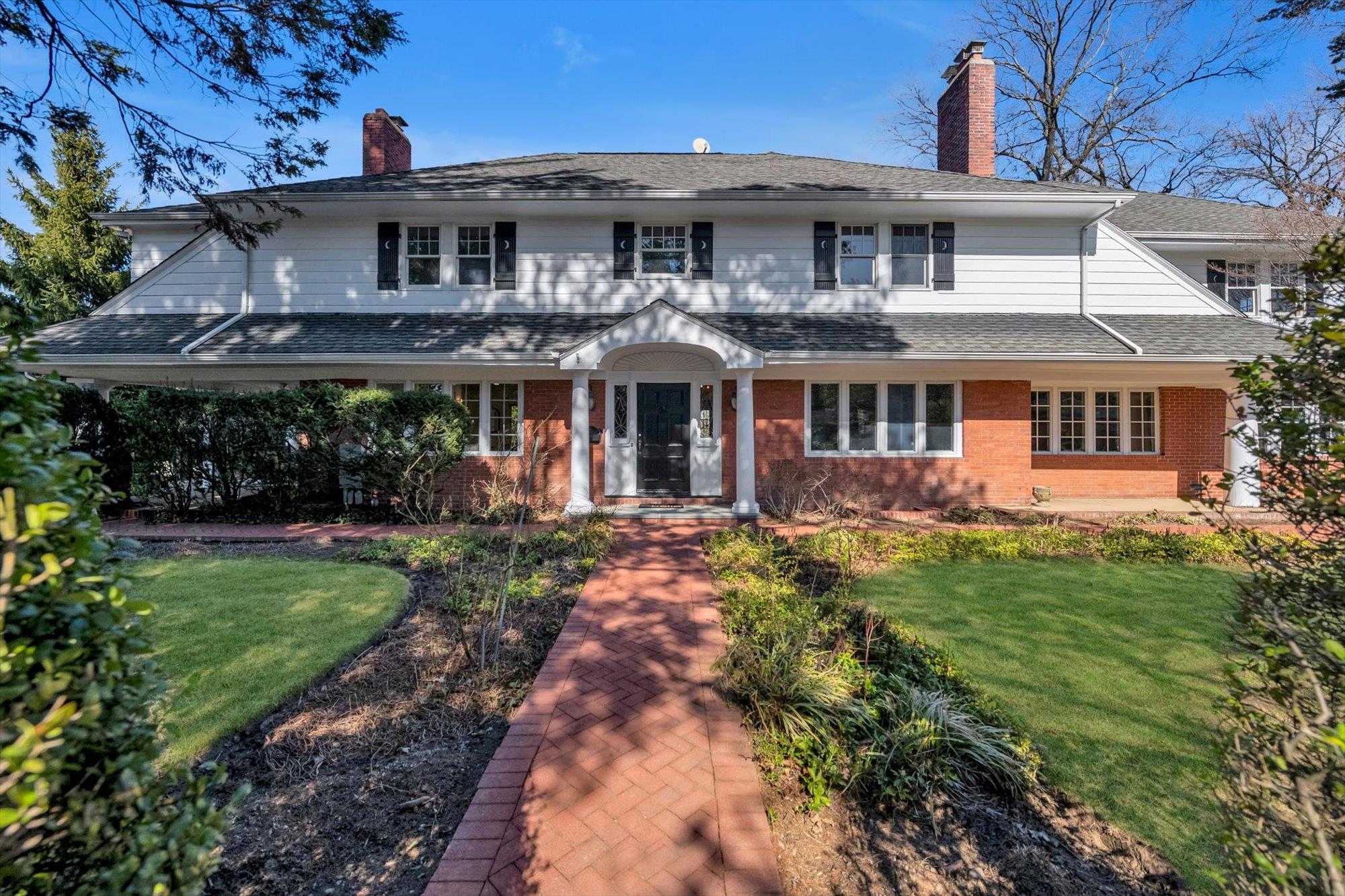 View of front of house with a chimney, a shingled roof, brick siding, and a front yard