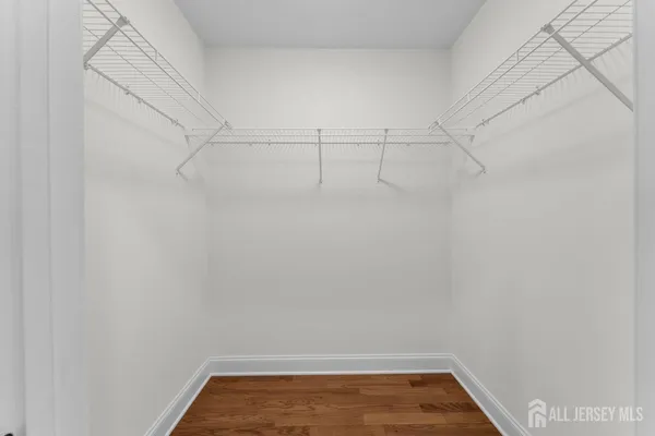 a view of an empty room with wooden floor and closet