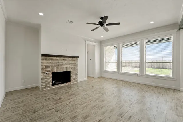 a view of an empty room with a window and fireplace