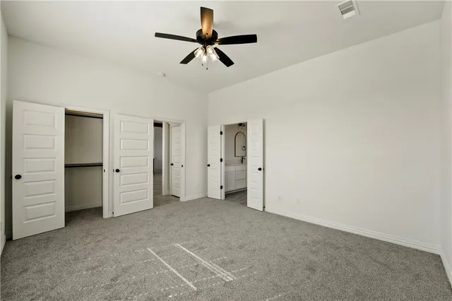 an empty room with closet and a ceiling fan