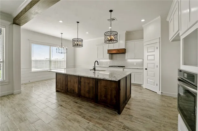 a kitchen with stainless steel appliances granite countertop a sink a stove and a wooden floors