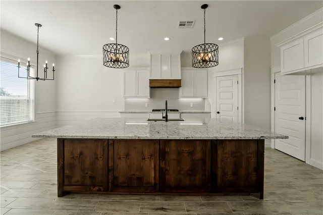 a view of kitchen with granite countertop cabinets a sink and a chandelier