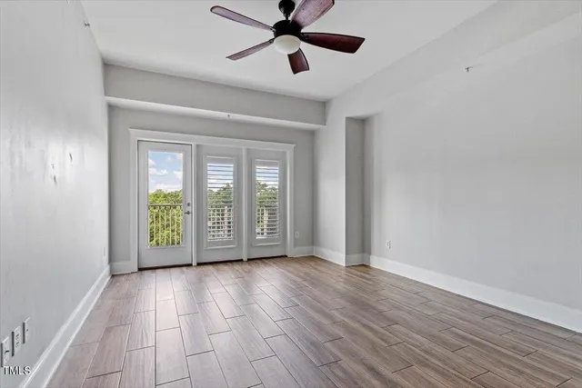 a view of an empty room with a window and wooden floor