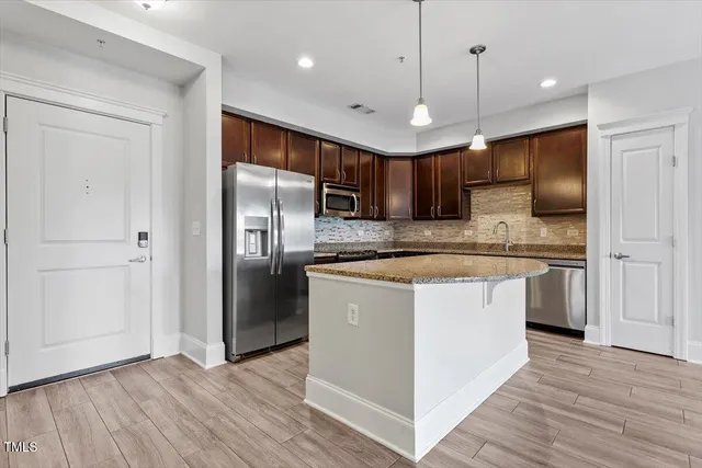 a kitchen with kitchen island a counter space a refrigerator and a sink