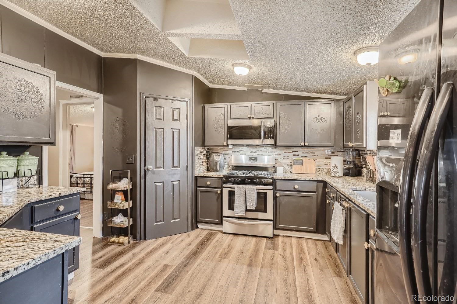 a kitchen with stainless steel appliances granite countertop a refrigerator stove top oven and sink