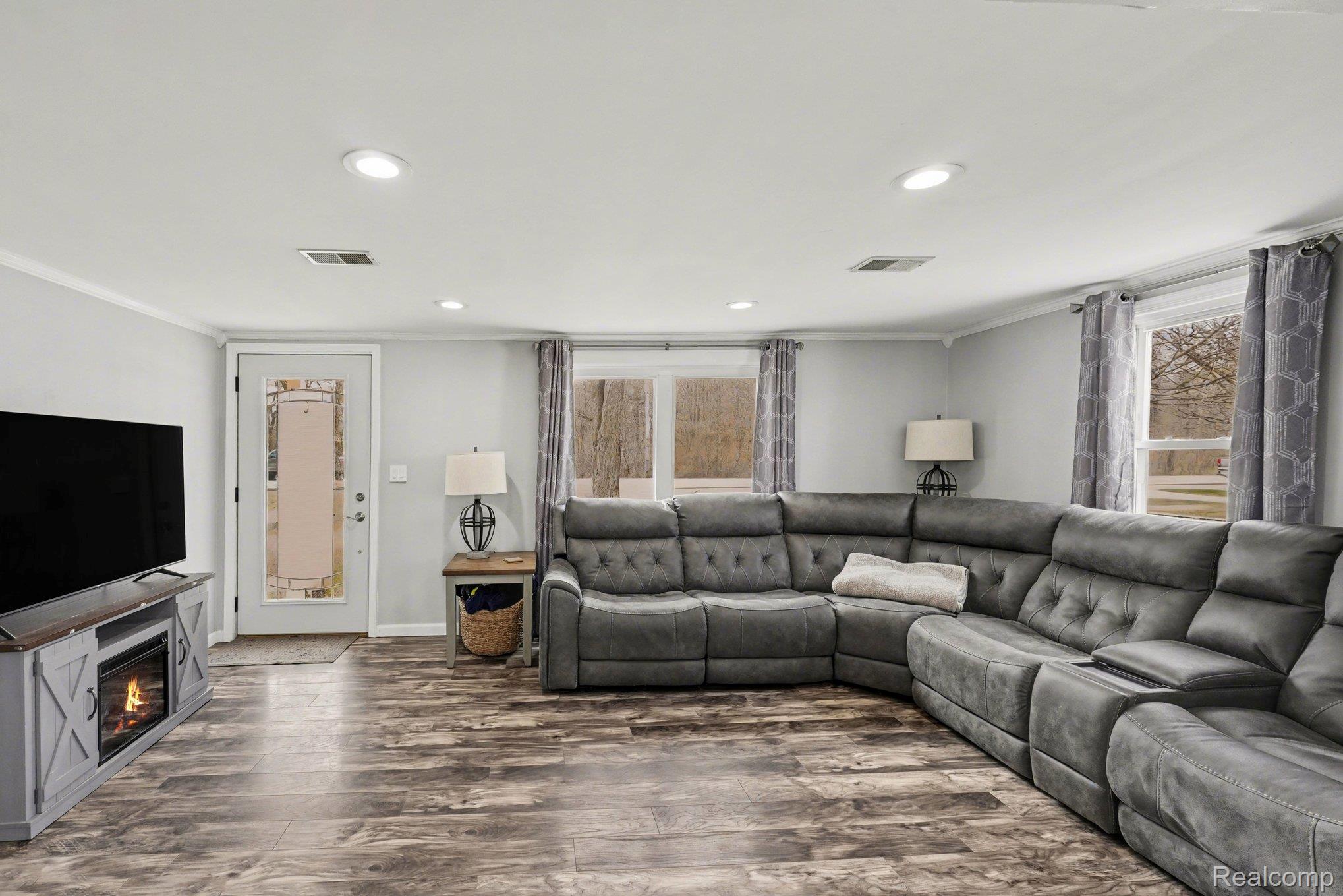 16485 Jennings Road Fenton, MI 48430 - Photo 10 of 27 Living area with ornamental molding, wood finished floors, plenty of natural light, recessed lighting, and a glass covered fireplace