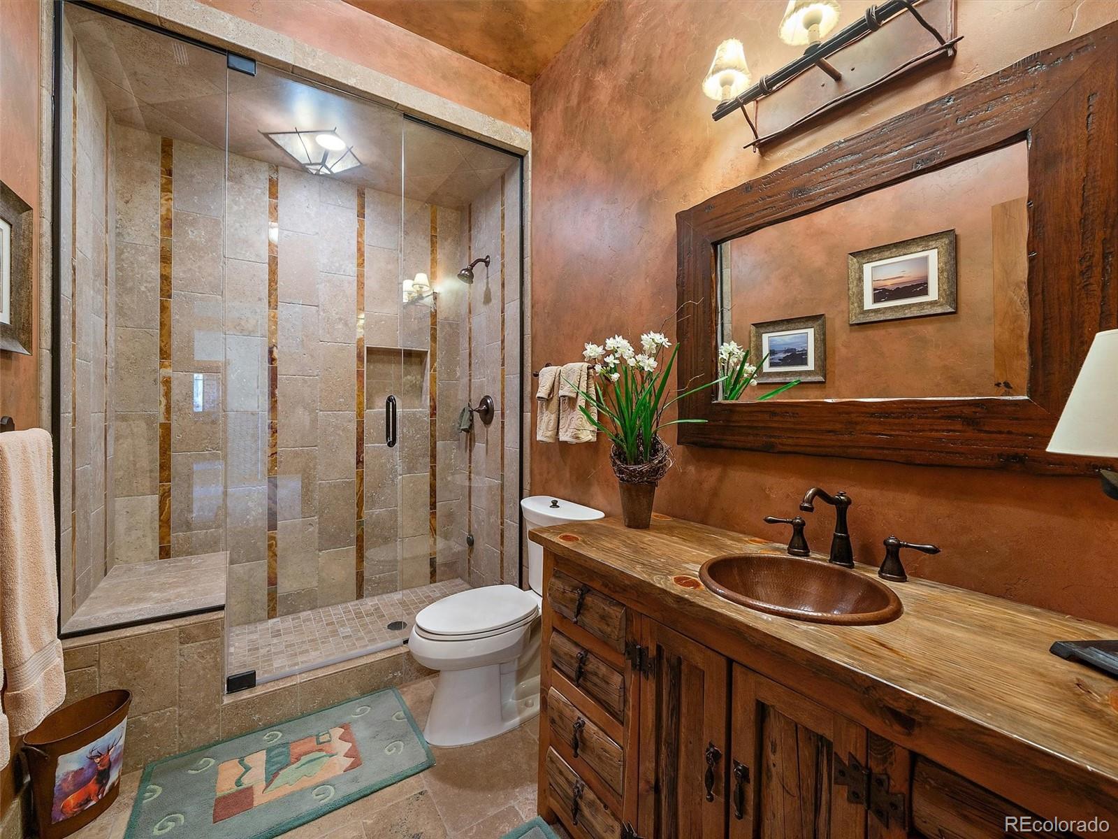 451 Bear Meadow Trail Evergreen, CO 80439 - Photo 25 of 45 a bathroom with a granite countertop sink a toilet a mirror and shower