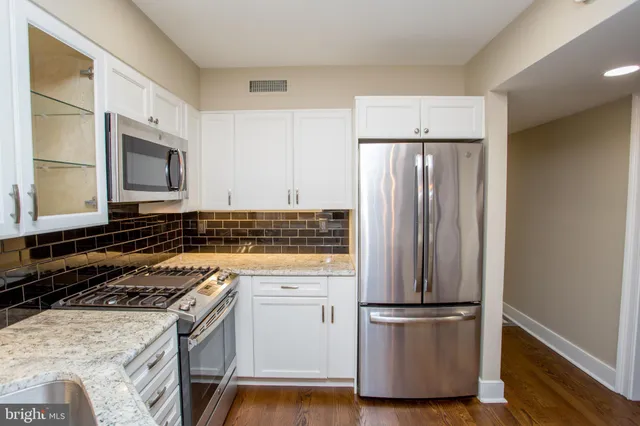 a kitchen with stainless steel appliances granite countertop a refrigerator and a stove top oven