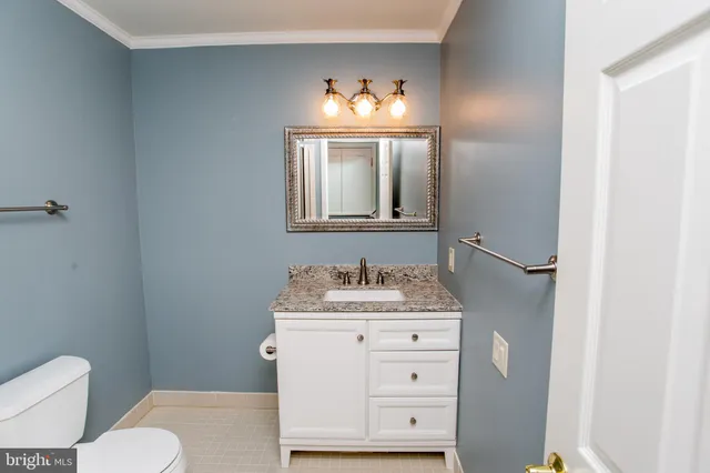 a bathroom with a granite countertop sink and a toilet