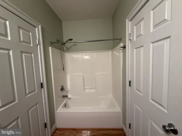 a view of a hallway to a room with wooden floor and stairs