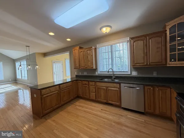 a large kitchen with stainless steel appliances granite countertop a stove a sink dishwasher and wooden cabinets with wooden floor
