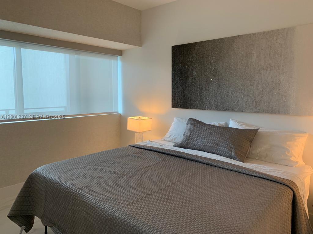 650 Northeast 32nd Street, Unit 705 Miami, FL 33137 - Photo 8 of 24 a bed sitting in a bedroom next to a window