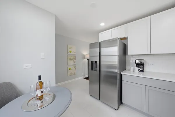 a kitchen with stainless steel appliances a refrigerator a sink a stove a dining table and chairs