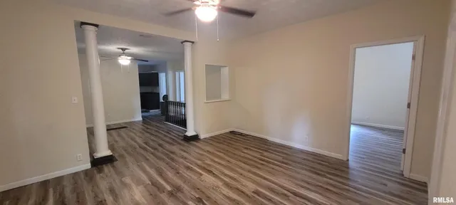 an empty room with wooden floor and a ceiling fan