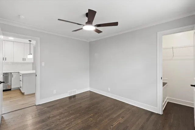 an empty room with wooden floor and a ceiling fan