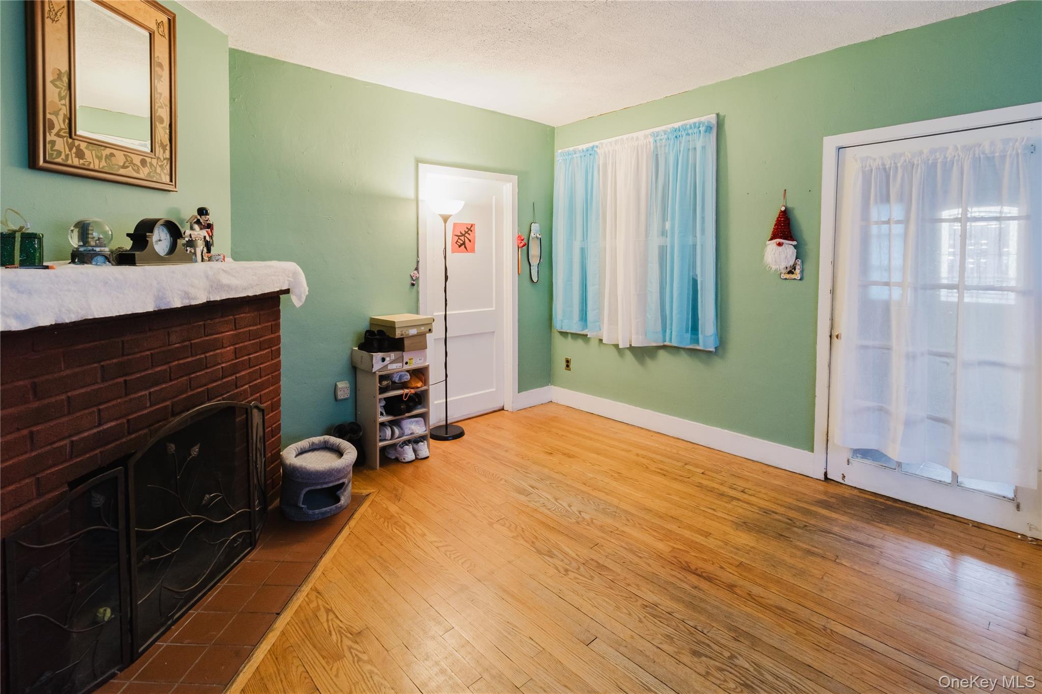 6 Stowe Road Peekskill, NY 10566 - Photo 6 of 17 Living room featuring a brick fireplace, light wood-style flooring, and a textured ceiling