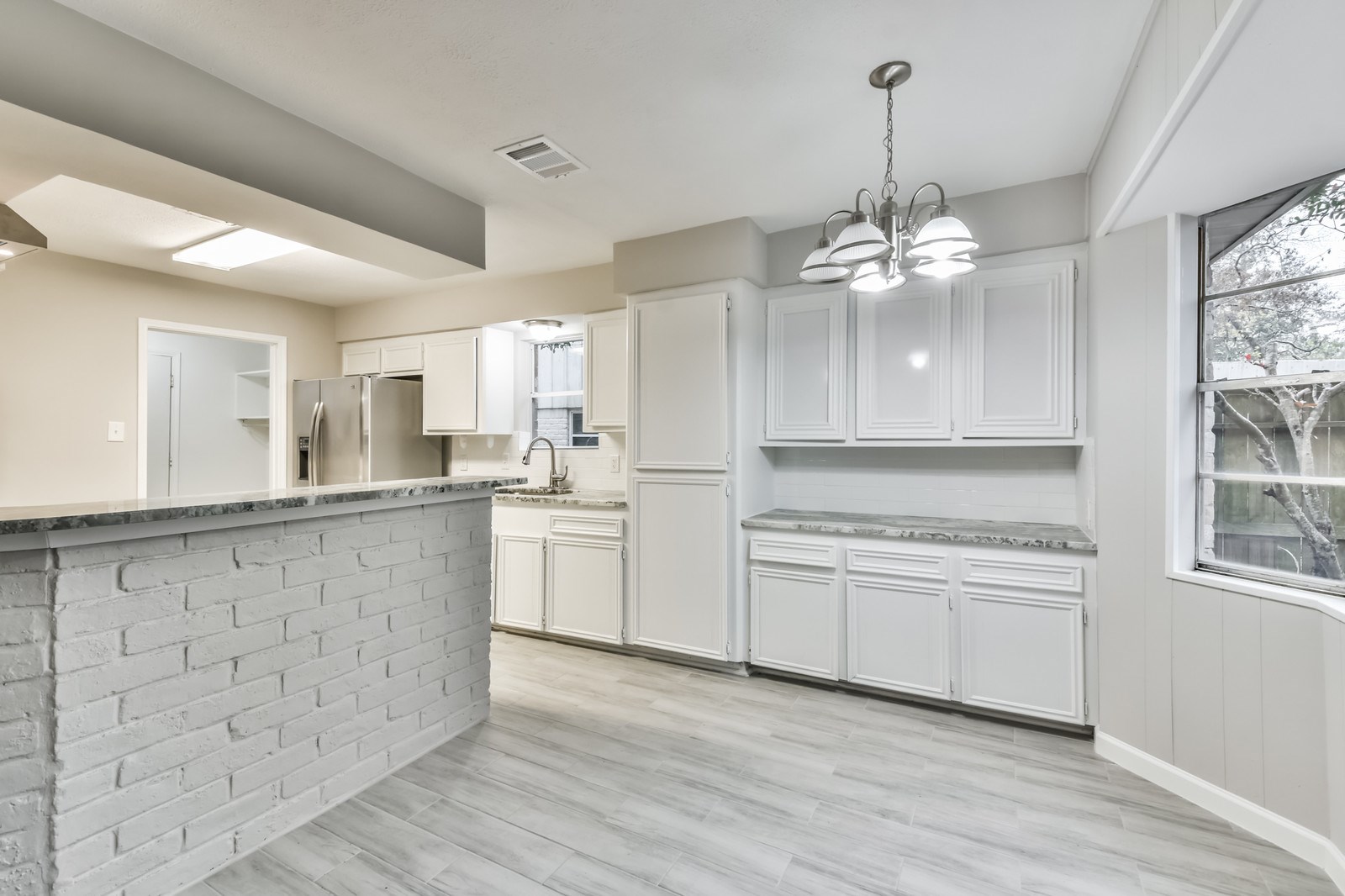 9718 John Bank Drive Spring, TX 77379 - Photo 20 of 39 a large kitchen with granite countertop a stove a sink dishwasher a refrigerator and white cabinets with wooden floor
