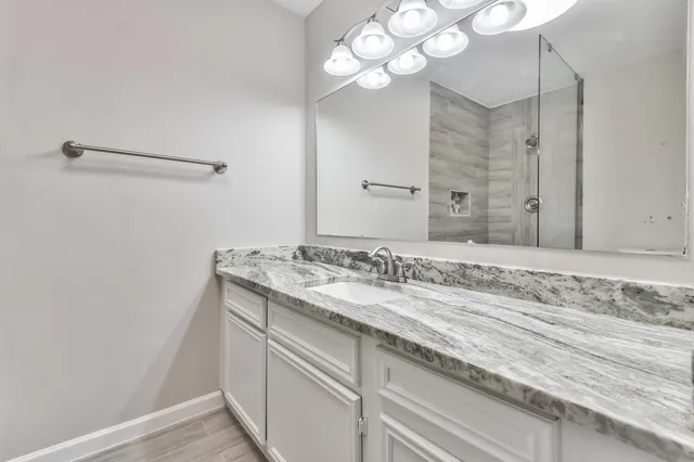 a bathroom with a granite countertop sink a mirror and vanity