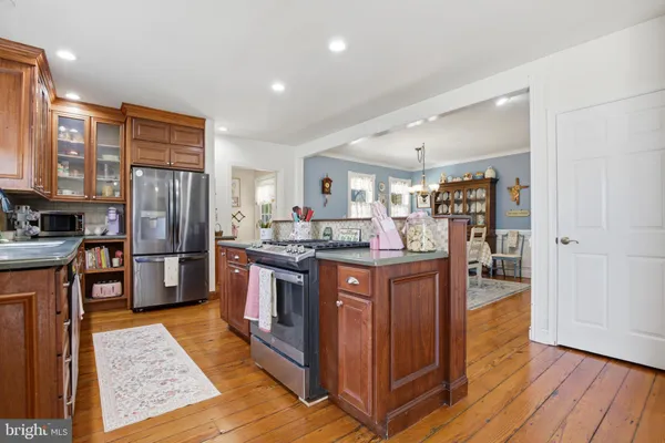 a kitchen with stainless steel appliances granite countertop a refrigerator a stove and a wooden floors