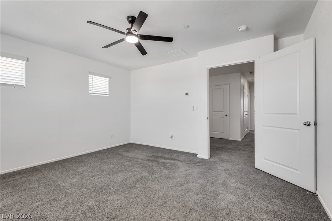 1114 Scarlet Sparrow Street Henderson, NV 89011 - Photo 15 of 25 Comfortable carpeted bedroom with a modern ceiling fan and natural illumination.