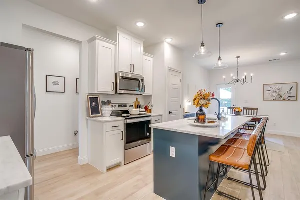 a kitchen with stainless steel appliances kitchen island granite countertop a sink a stove a dining table and chairs