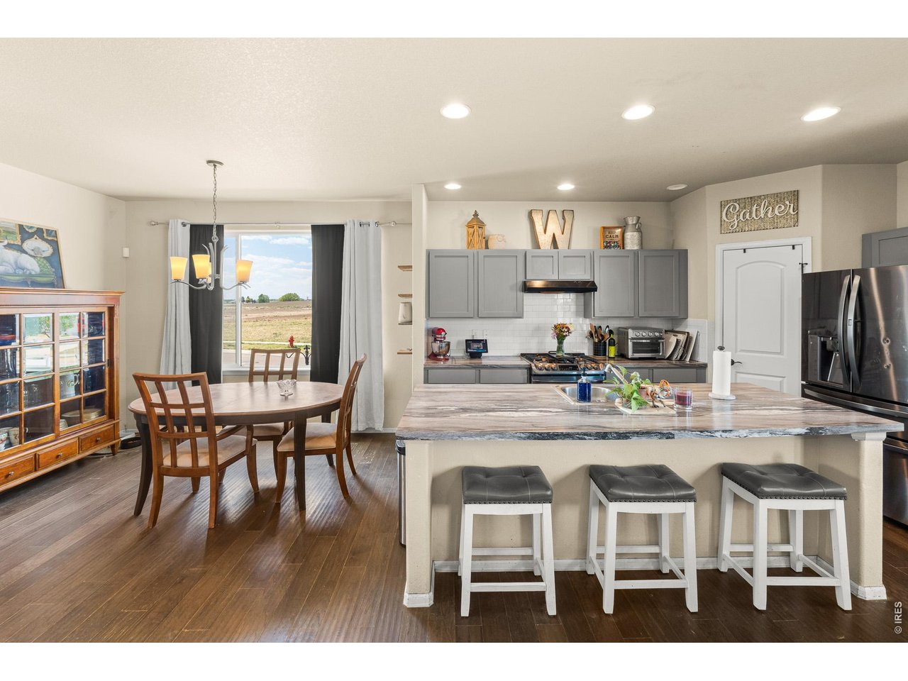 8847 16th St Road Greeley, CO 80634 - Photo 16 of 38 a kitchen with stainless steel appliances granite countertop dining table chairs and wooden floor