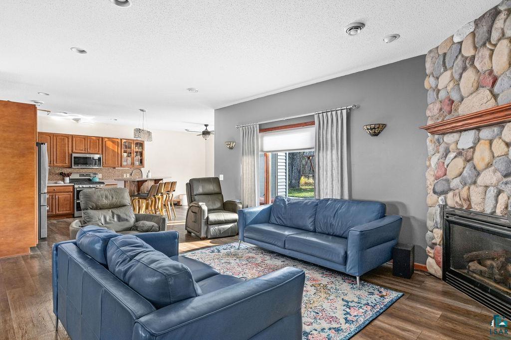 6048 Lakewood Road Duluth, MN 55804 - Photo 25 of 65 Living room featuring dark wood-style flooring, a textured ceiling, a fireplace, and a ceiling fan