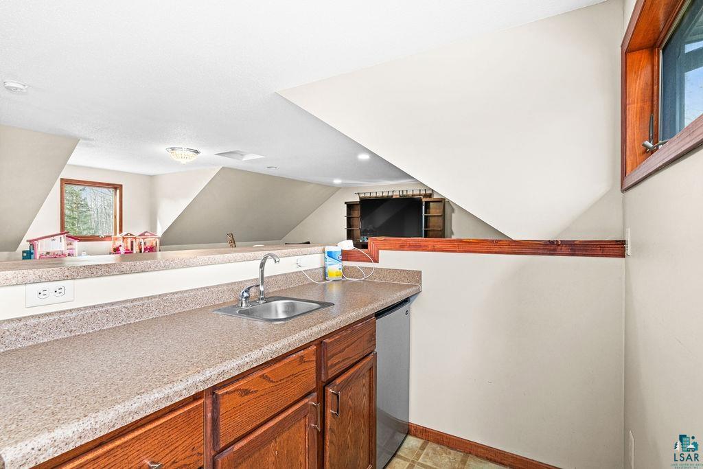 6048 Lakewood Road Duluth, MN 55804 - Photo 65 of 65 Kitchen with light countertops, brown cabinetry, dishwasher, open floor plan, and vaulted ceiling