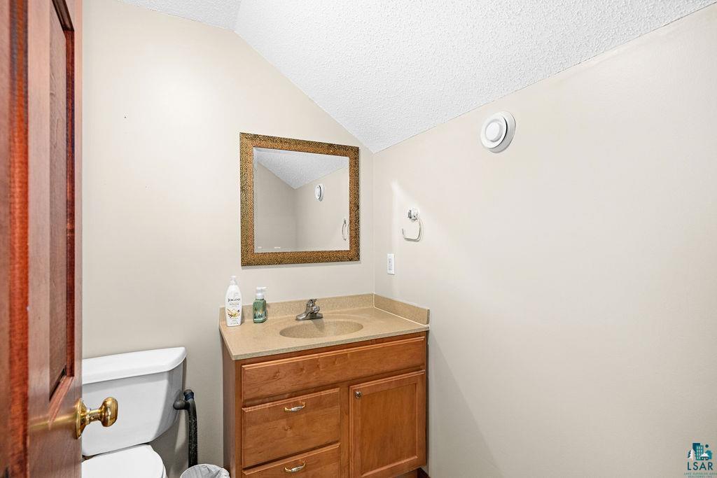 6048 Lakewood Road Duluth, MN 55804 - Photo 38 of 65 Half bathroom with a textured ceiling, vanity, and lofted ceiling