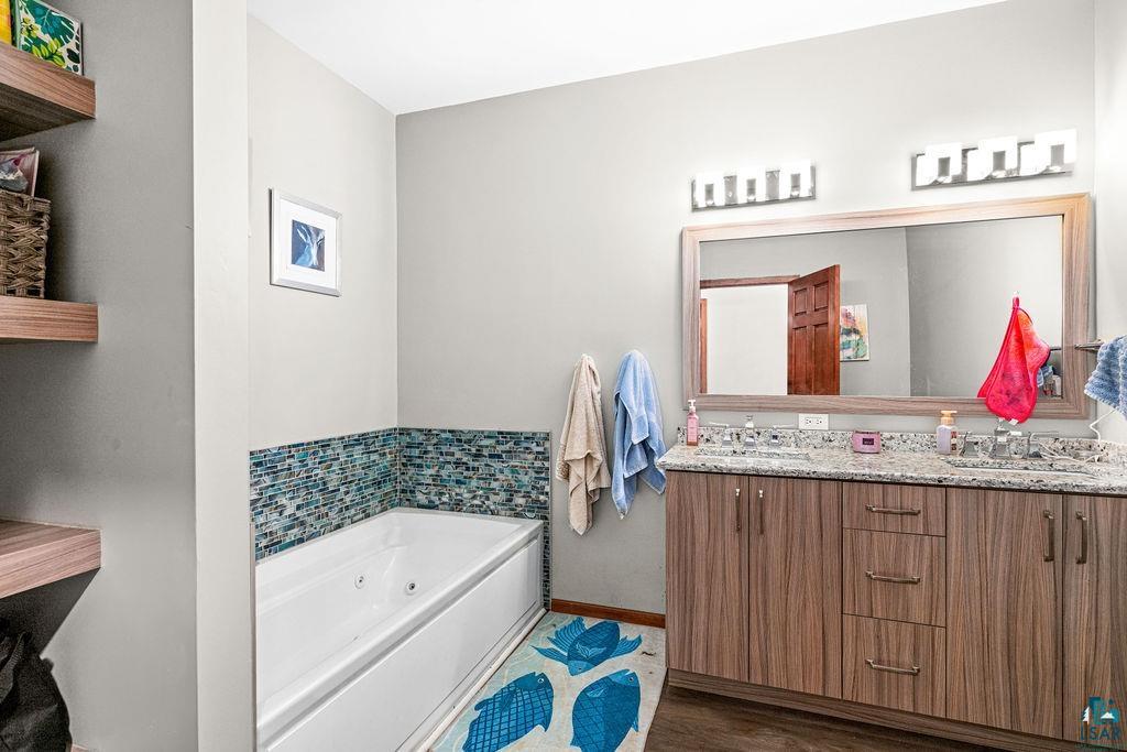 6048 Lakewood Road Duluth, MN 55804 - Photo 48 of 65 Full bath featuring double vanity, a jetted tub, and dark wood finished floors