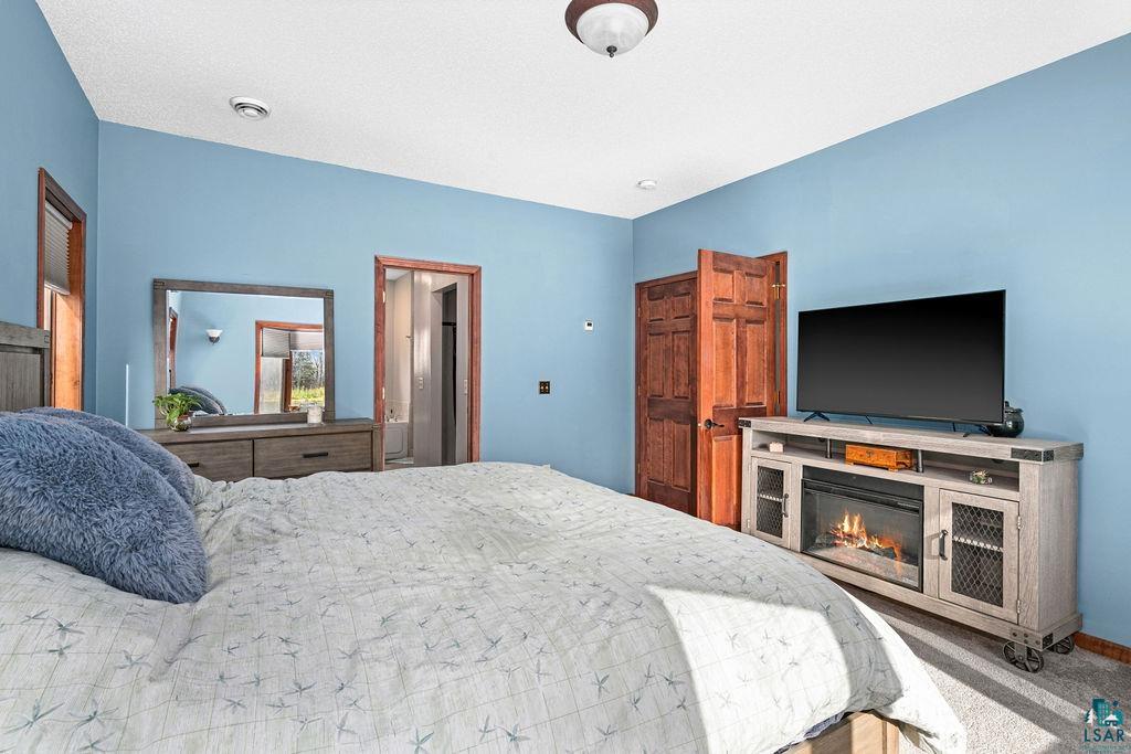 6048 Lakewood Road Duluth, MN 55804 - Photo 58 of 65 Carpeted bedroom featuring a glass covered fireplace and baseboards