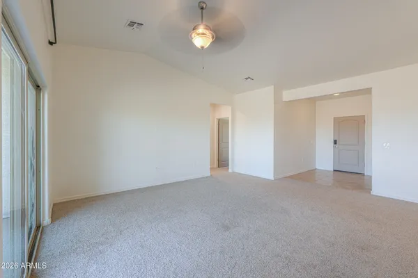 an empty room with chandelier fan and windows