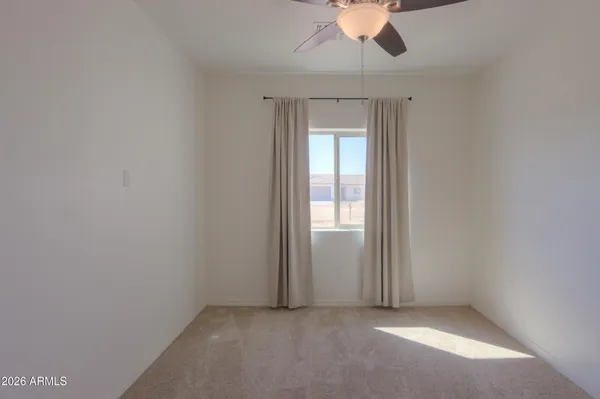 a view of an empty room with a chandelier fan