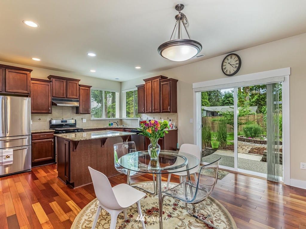 5111 Northeast 25th Street Renton, WA 98059 - Photo 13 of 29 a kitchen with stainless steel appliances granite countertop wooden floor dining table and chairs