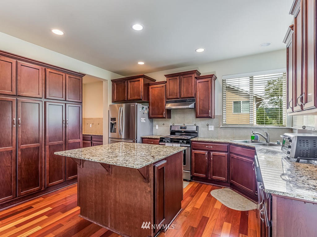 5111 Northeast 25th Street Renton, WA 98059 - Photo 8 of 29 a kitchen with stainless steel appliances granite countertop a sink stove refrigerator and cabinets