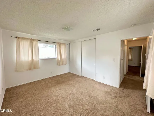 a view of an empty room with window and closet area
