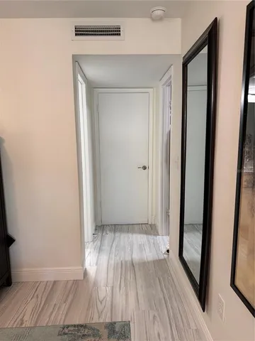 a view of a hallway with wooden floor and a bathroom